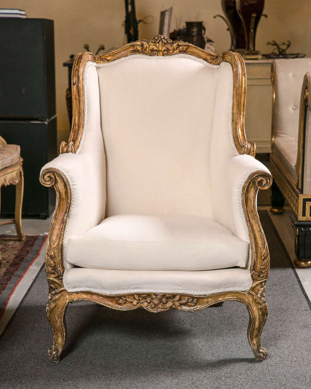 Pair of alluring Vintage French wingback Bergere chairs in the Rococo taste, circa 1930s, decorated in its original distressed and gilt frame, the domed back with shell crest conforming winged sides extending to rolled arms, new upholstery and