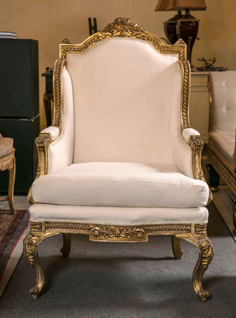 Absolutely stunning pair of French Louis XV style bergère chairs, circa 1930s, decorated in elegant gilt finish. The domed back with annulated carvings surmounted by foliate and ribbon crest conforming winged sides, joint by cushioned seat, raised