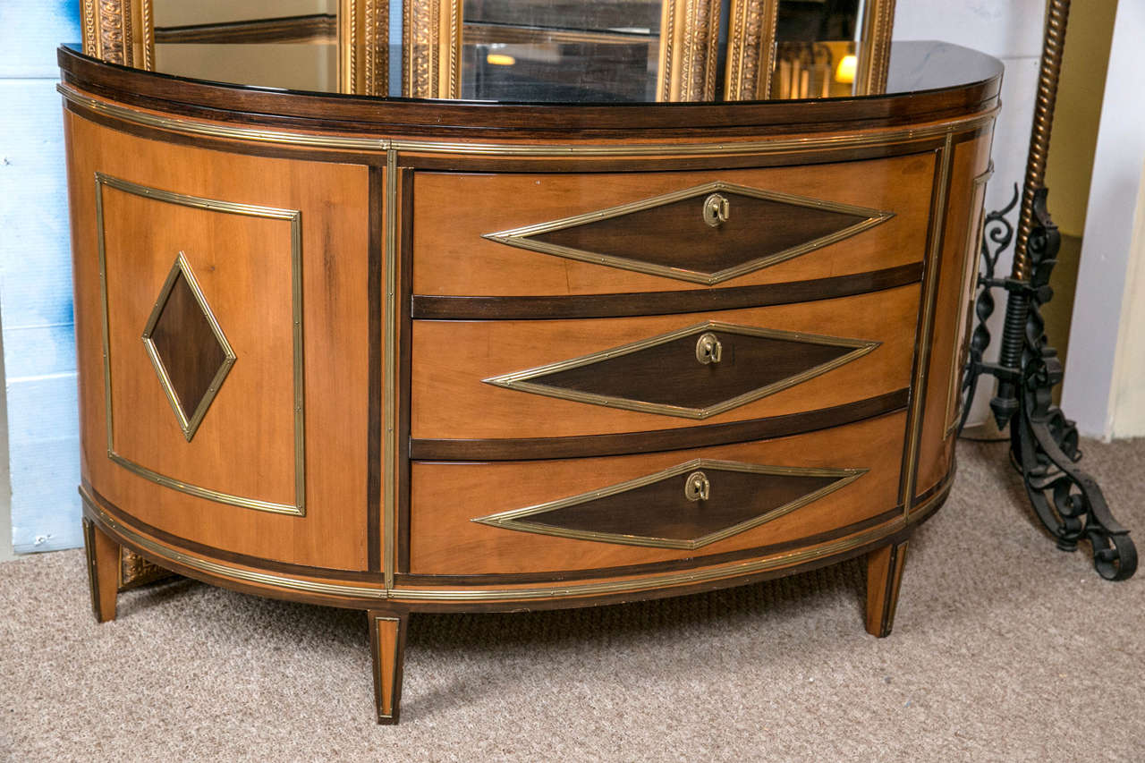 An attractive Russian neoclassical style demilune chest or commode, second quarter of the 20th century. The half-moon shaped top covered with a smokey glass over a finely polished walnut finish, above a conforming case fitted with three demilune