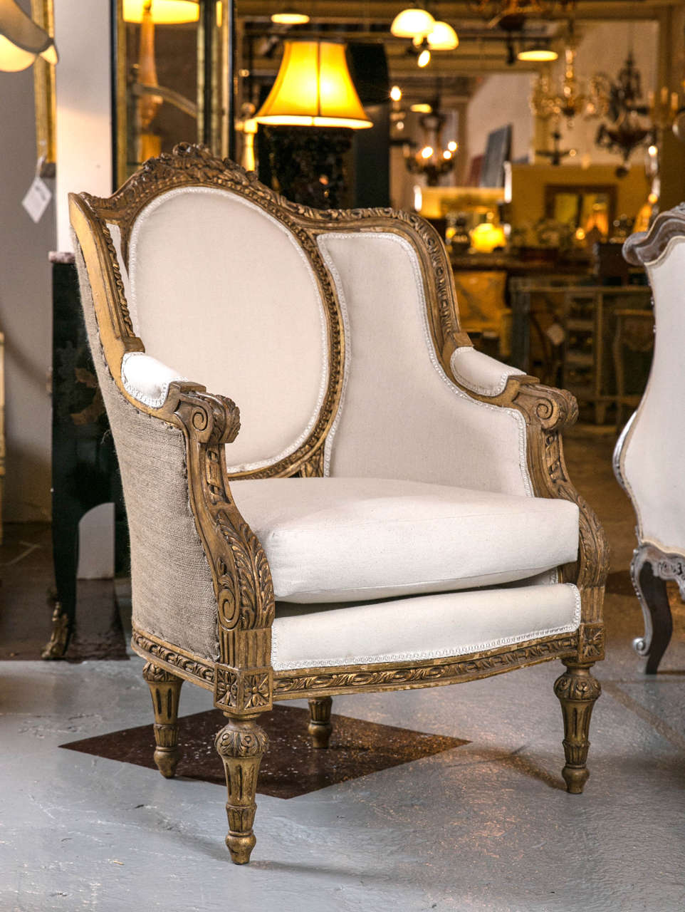 Pair of gorgeous French Louis XVI style bergère chairs, circa 1940s, original subtle gilt finish and beautiful carving, the oval medallion backrest and down-swept arms, cushioned seat, raised on tapering bulbous legs.