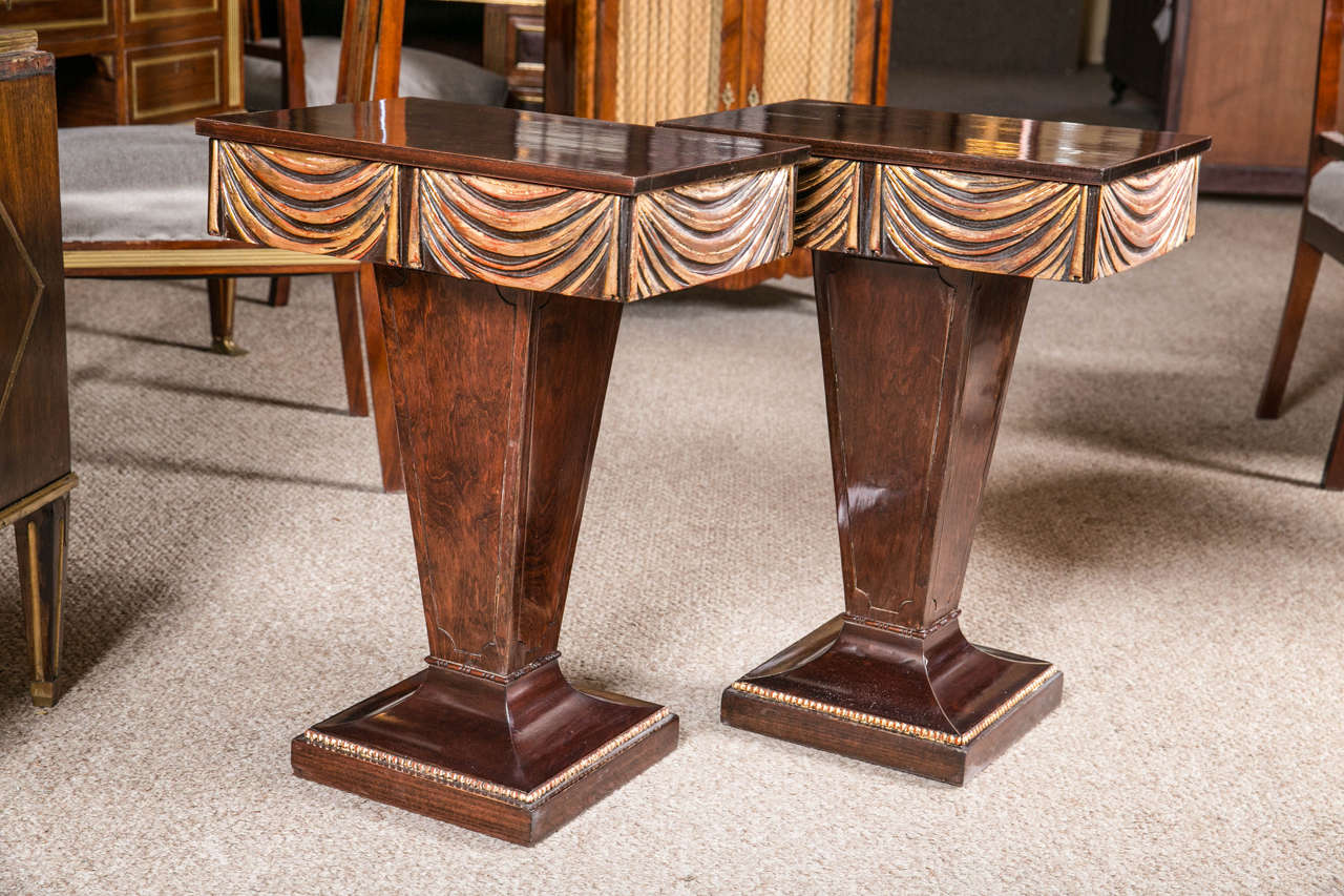 This simply stunning pair of Grosfeld House Hollywood Regency era end / night tables would make an incredible statement in any setting of the house. The singular pedestal tapering base supported by a wider square footing decorated with gilt gold