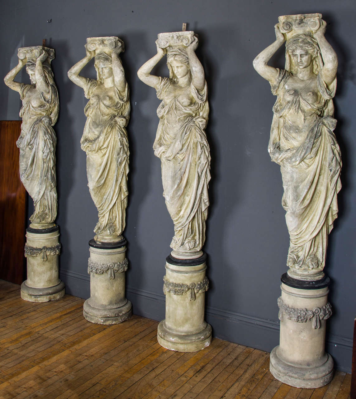 A beautiful and elaborate set of 4 caryatids of plaster construction depicting ancient classical Greek female figures supporting Corinthian capitals standing on decorated bases. Each figure measures 80 in – 203.2 cm in height, 19 in – 48.2 cm wide
