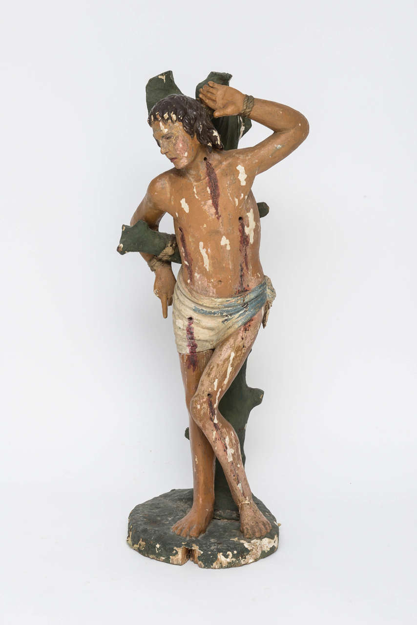 This large sculptural depiction of St. Sebastian who was martyred during the Christian persecutions by the Emperor Diocletian in the 3rd century.   One version of the story of his martyrdom has him tied to a tree while the archers of his regiment
