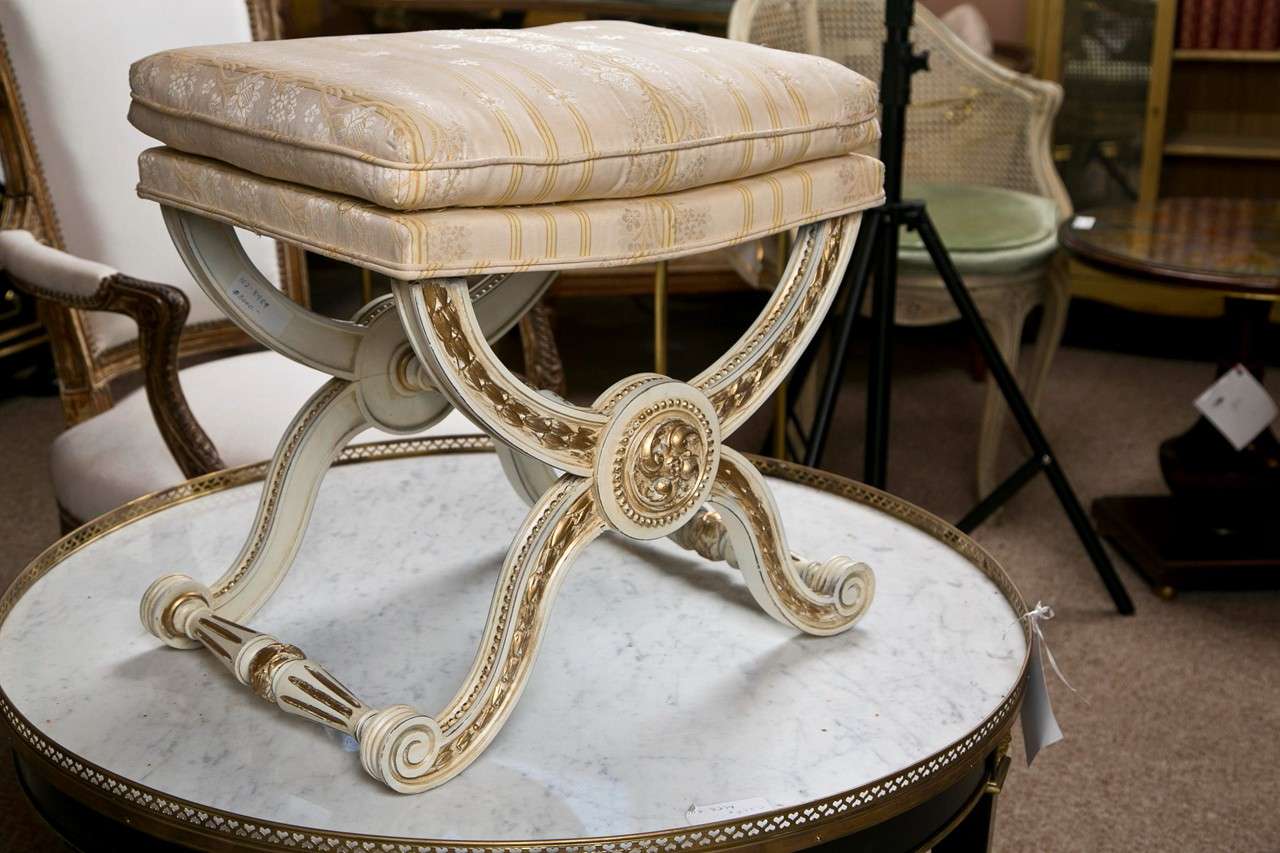 Pair of elegant X-base benches in the style of Hollywood Regency, circa 1960s, cushioned seat supported on painted and parcel-gilt base. 