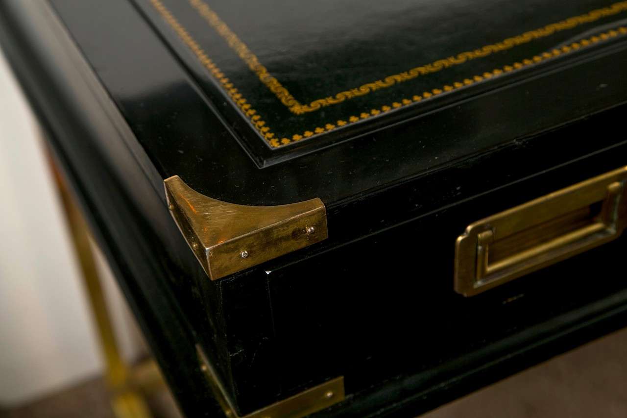 An attractive Hollywood Regency style ebonized desk, circa 1960s, the top ebonized with embossed leather writing surface, over a narrow frieze fitted with three drawers, raised on bronze columnar legs. By Jansen. 