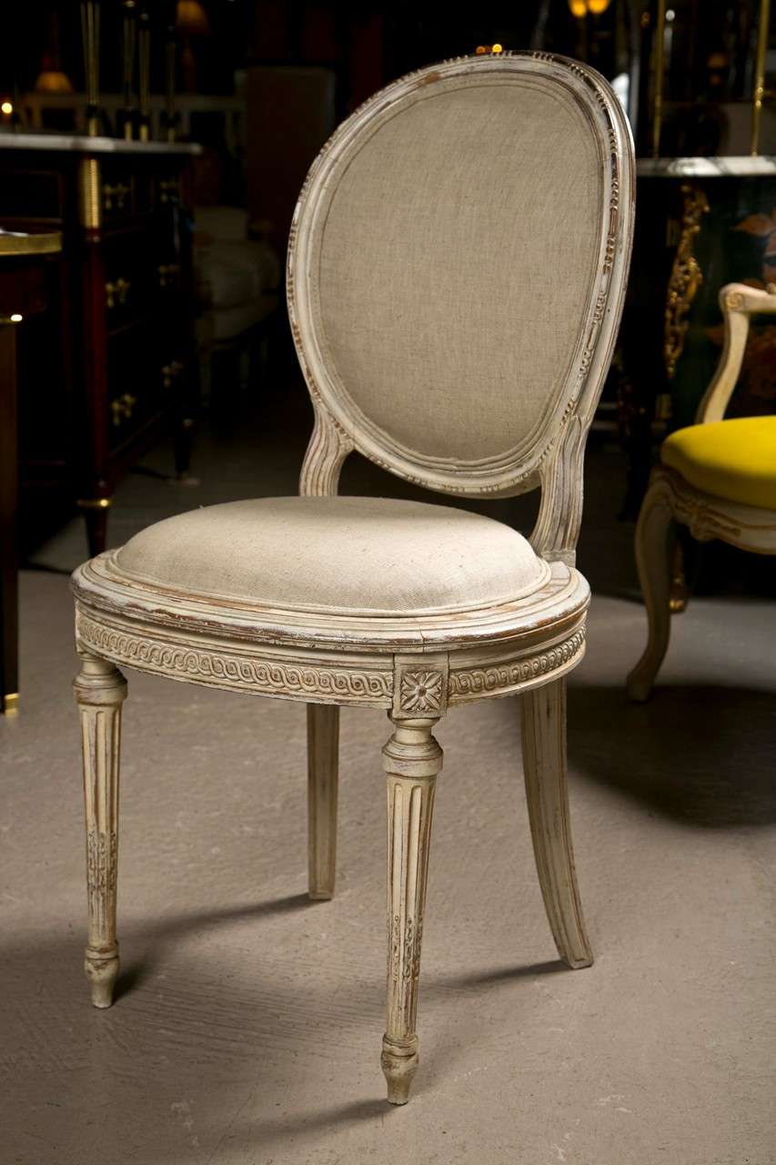 Set of 8 French Louis XVI style dining chairs, circa 1940s, this set consists 6 side chairs and 2 armchairs, distress-painted in off-white, oval padded back, the seat over a beautiful annulated-carved apron. By Maison Jansen.