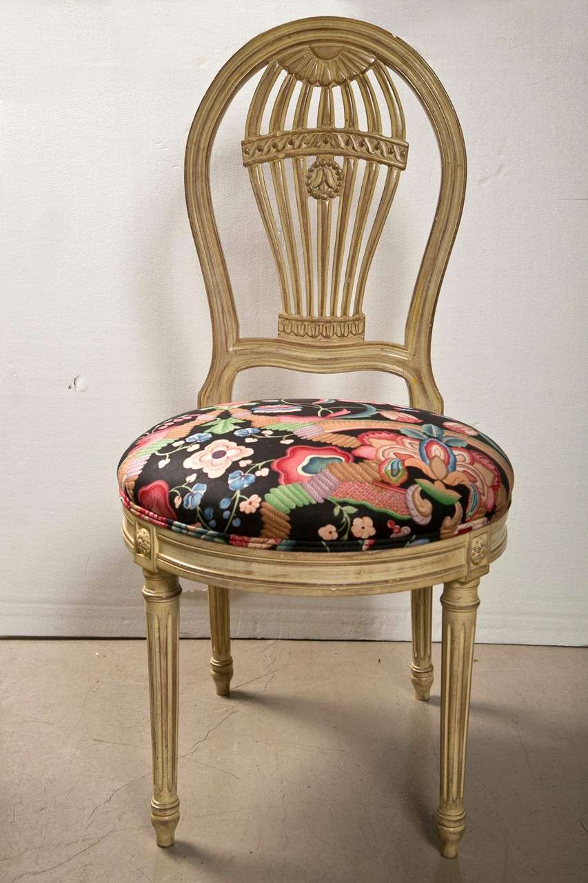 Set of 8 French dining chairs, circa 1940s, the set consists of 6 side chairs and 2 armchairs, the frame is distress-painted in off-white, upholstered in floral fabric, the black-splats in balloon motif, raised on fluted legs. By Jansen.