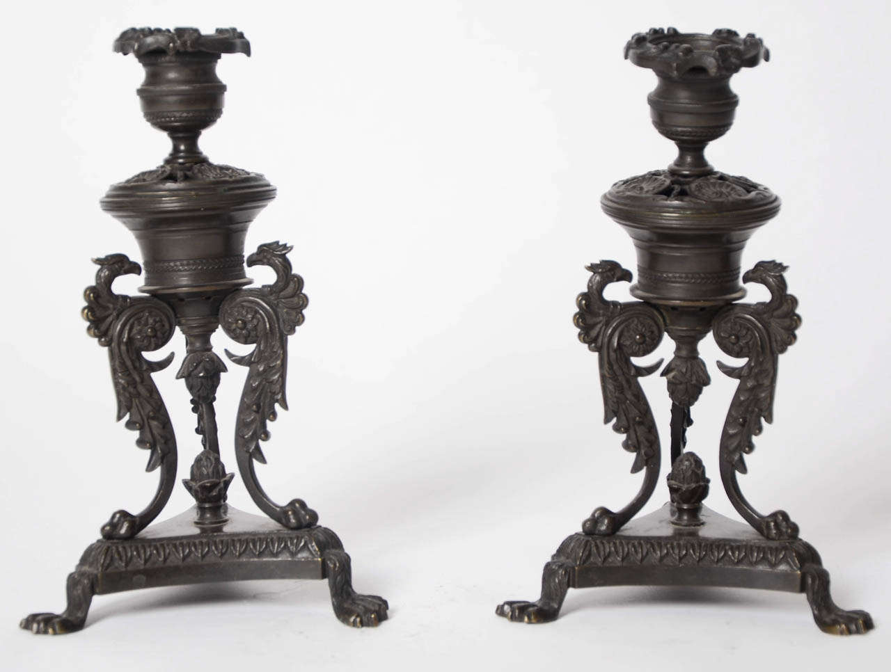 A pair of regency bronze candlesticks of classical mythological creature form on triform bases and claw feet.