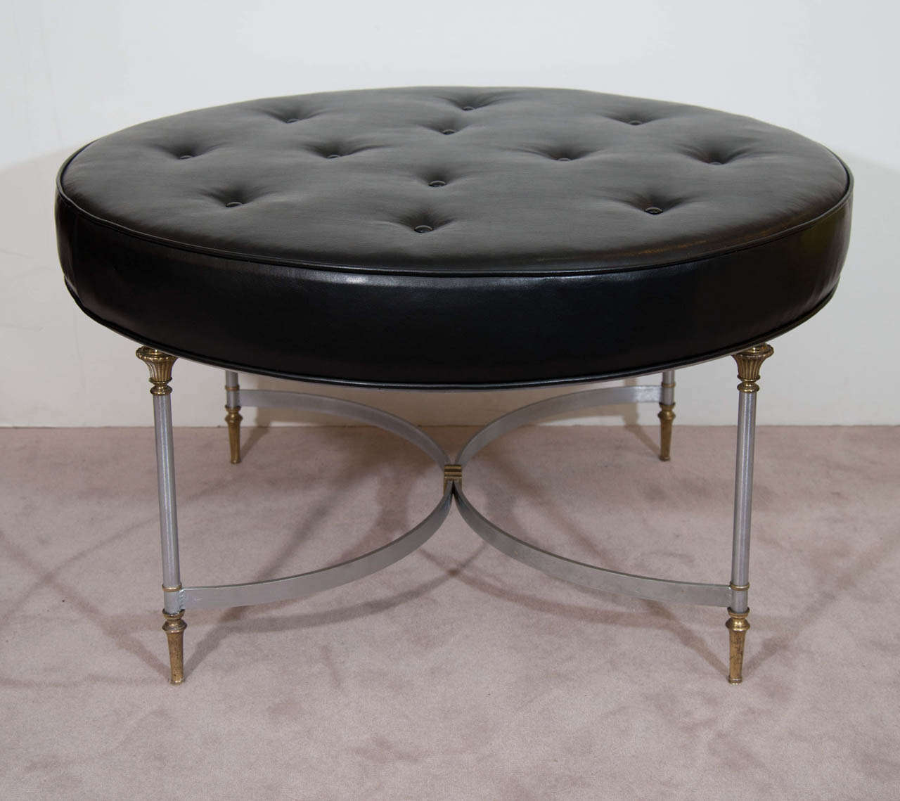 A vintage Maison Jansen circular ottoman with brushed steel frame and legs accented with brass. Cushion is newly upholstered with black leather. 

Good vintage condition with age appropriate wear. Slight wear to brass and brushed steel surfaces.