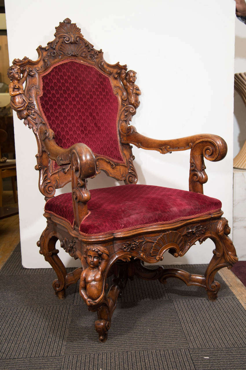 A 19th Century Italian Louis XV style wooden Fantasy armchair with carved shells and cherubs.  The chair is upholstered in a wine colored velvet.

Good condition with age appropriate wear.  Near the top the upholstery needs to be