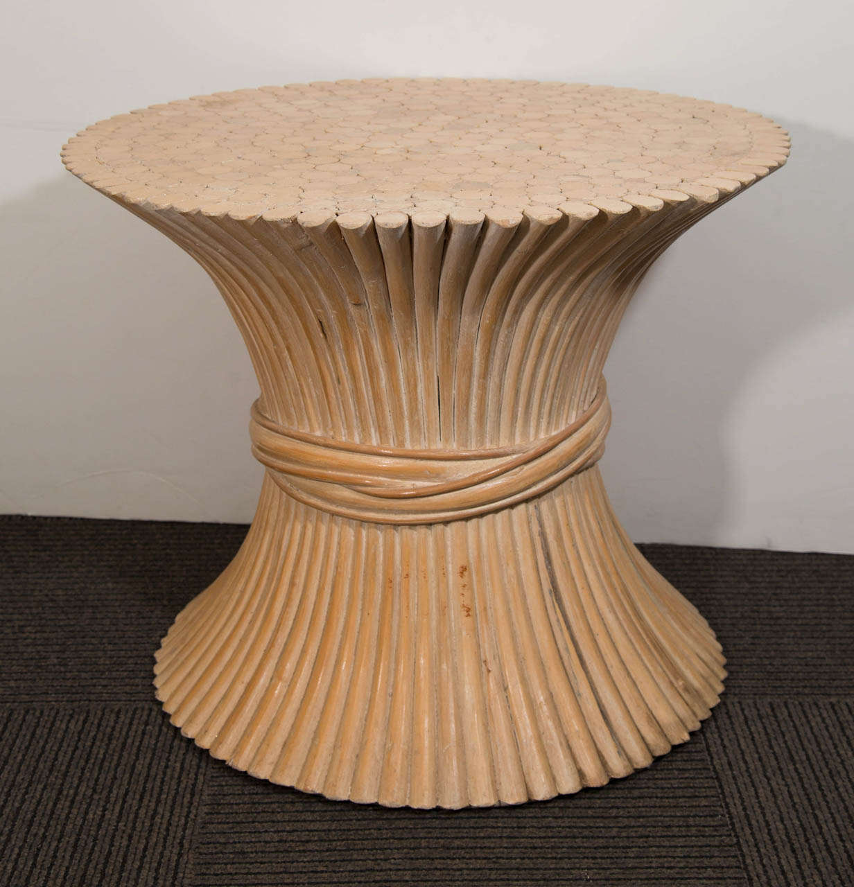 A vintage natural rattan side table in the form of a sheaf of wheat by McGuire.
Currently out of production. The base is handcrafted of Palasan rattan poles that are cinched in the middle by a heavy braid of rattan. The top surface is a beautiful