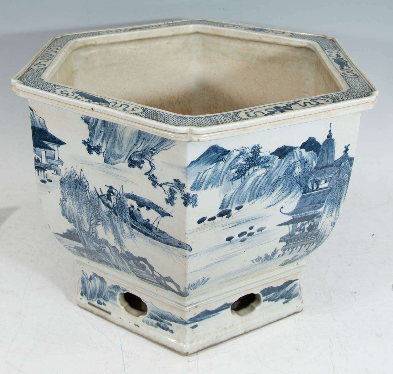 A late 18th or early 19th century six-sided Chinese porcelain planter painted in underglaze blue with pavilions and scenes of antique life.  The pierce-work base is integral with planter.

Good condition with age appropriate wear.  Some