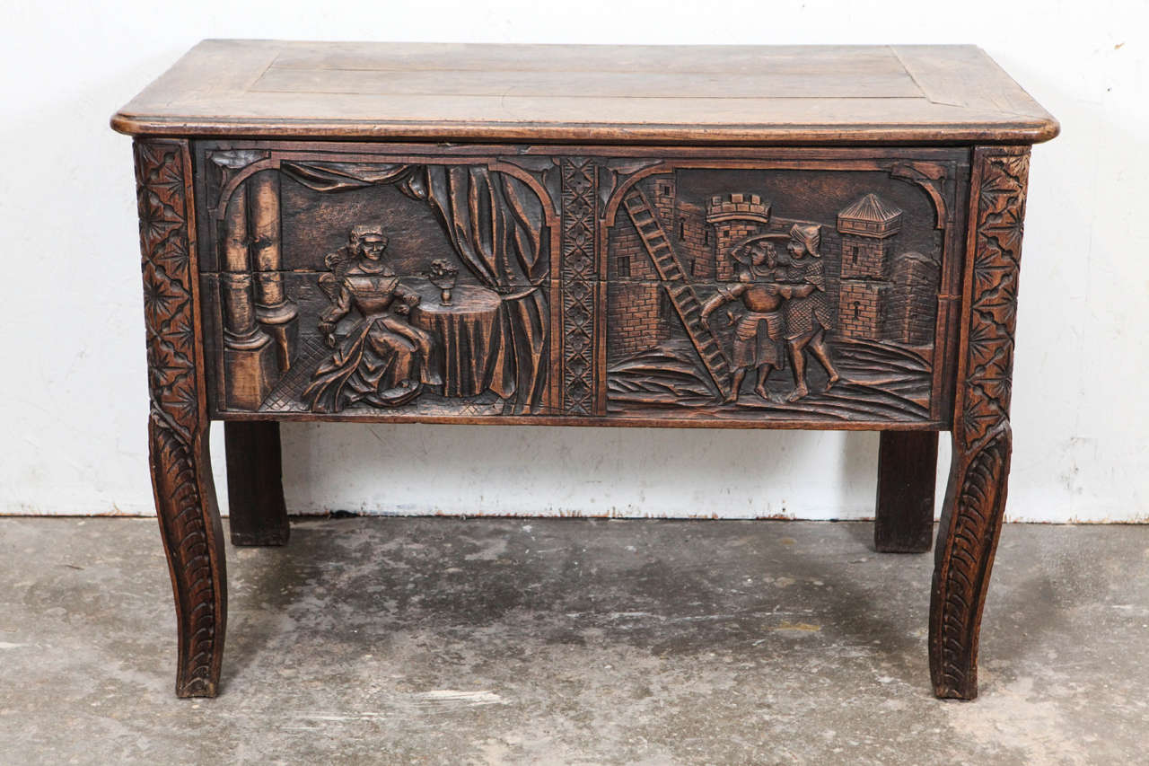 Tall wood trunk with pivoting top / lid and carved medieval Gothic scene on front.