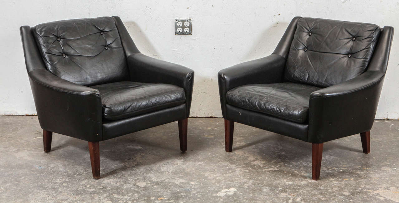 Handsome Mid-Century black leather armchairs with tufted back cushions.