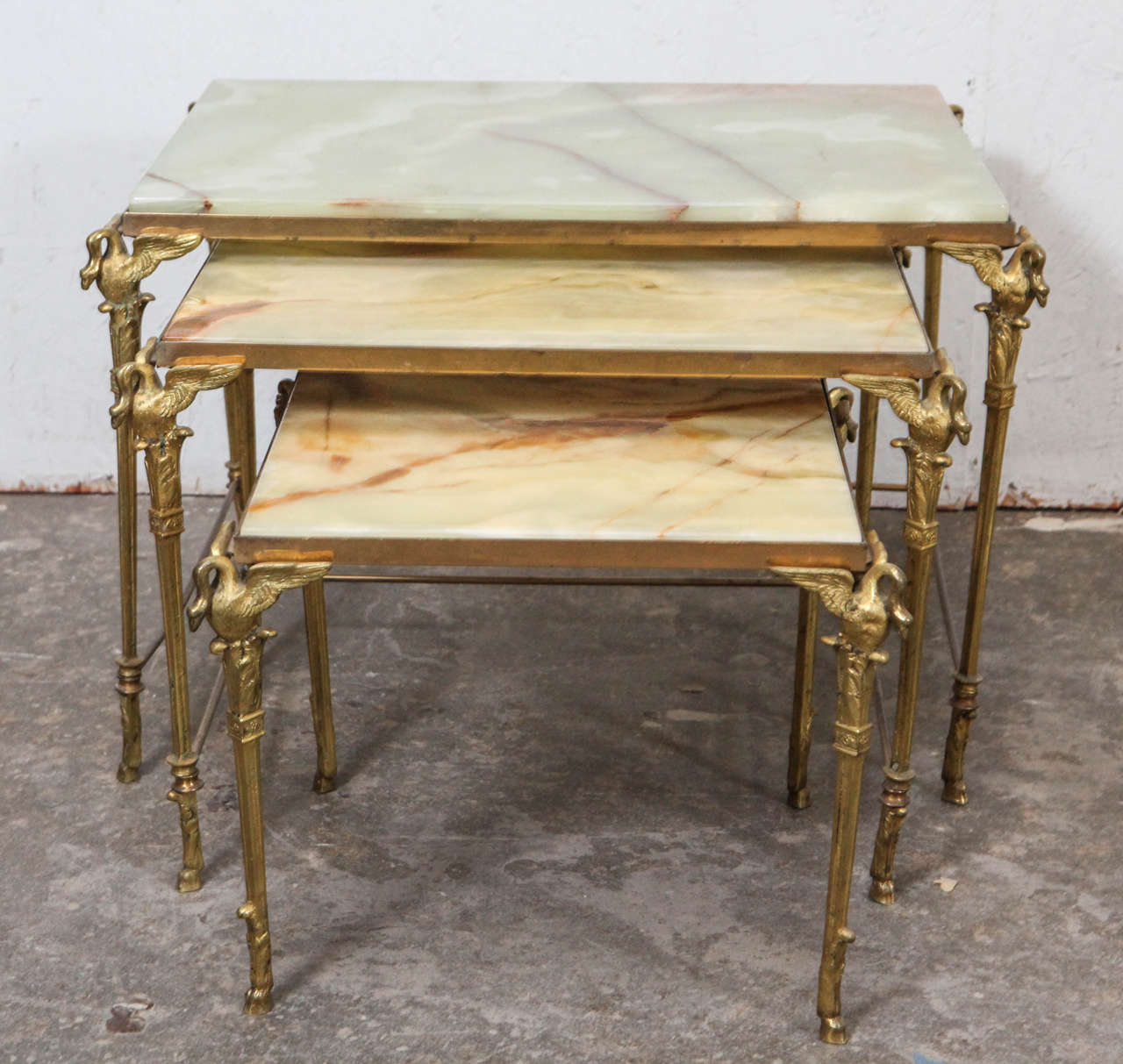 Beautiful brass nesting tables with elegant swan details and rare green and peach toned onyx tops.