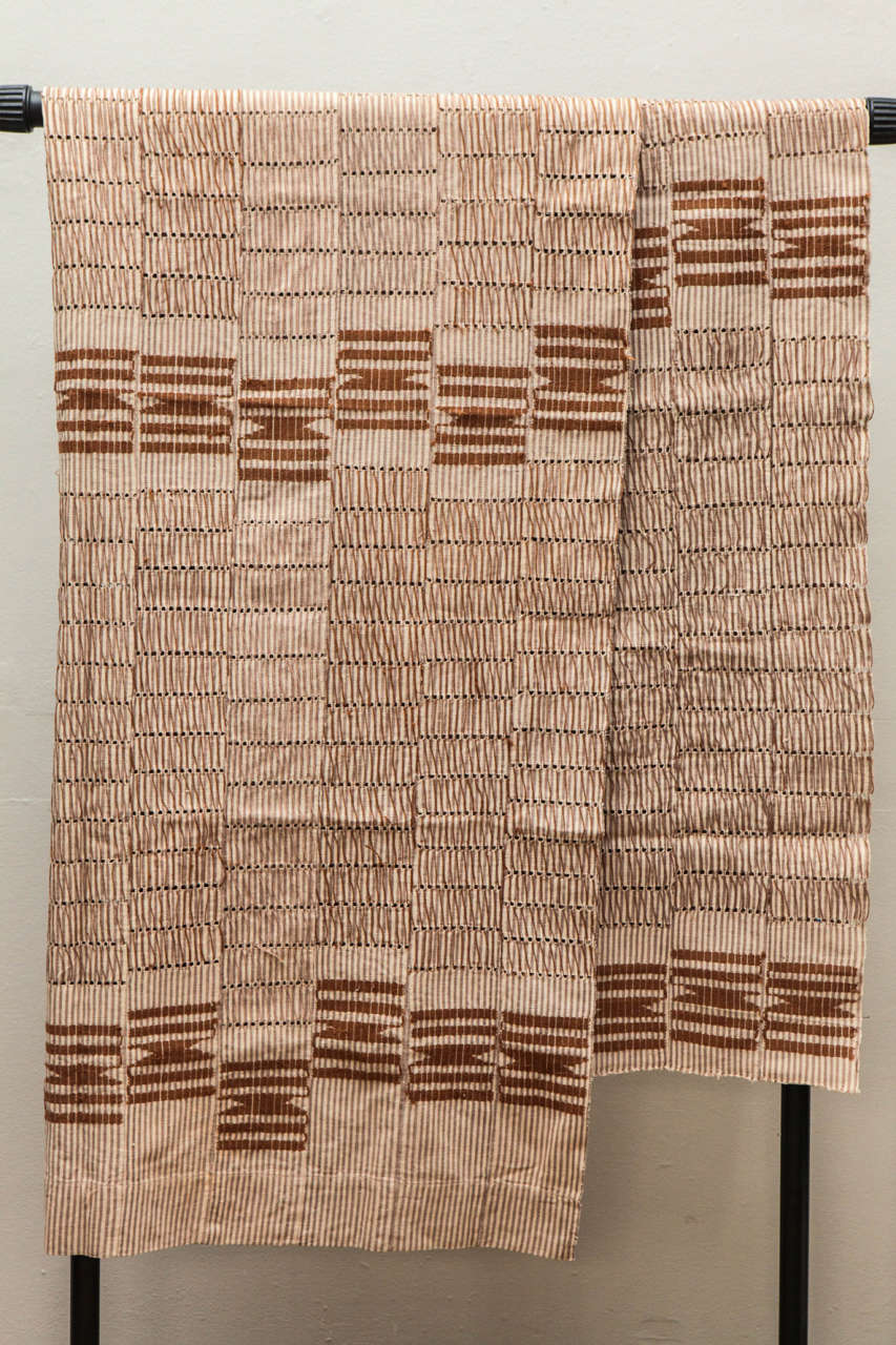 Tessuti e ricamati a mano, tessuti stretti, lavorati a telaio a strisce e cuciti insieme per creare grandi pannelli. Realizzato dal popolo Yoruba della Nigeria.  Strisce marroni con abbellimenti color caramello.  Cotone.  Due disponibili a 450