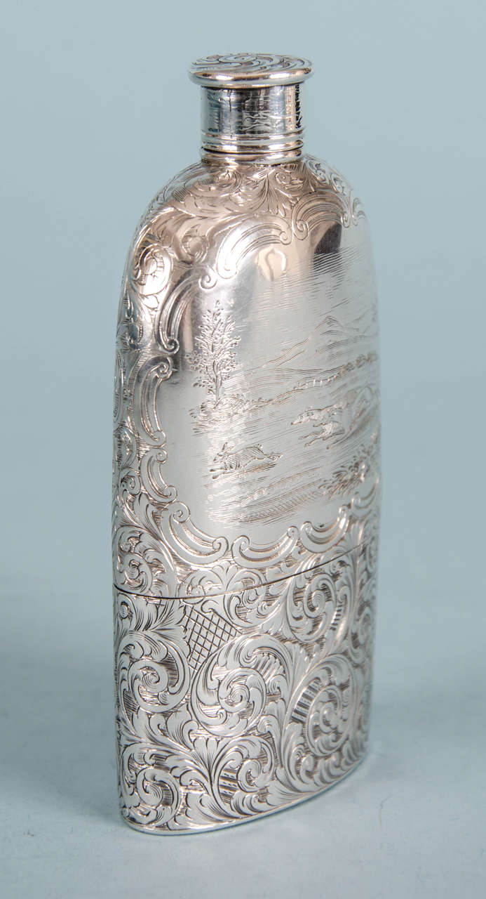 Beautifully engraved sterling silver Victorian hip flask with screw on lid and detachable cup.
Makers: Yapp & Woodward, Birmingham, 1854.

One side of the flask is engraved with a hunting scene of hounds chasing a rabbit. The scene is surrounded