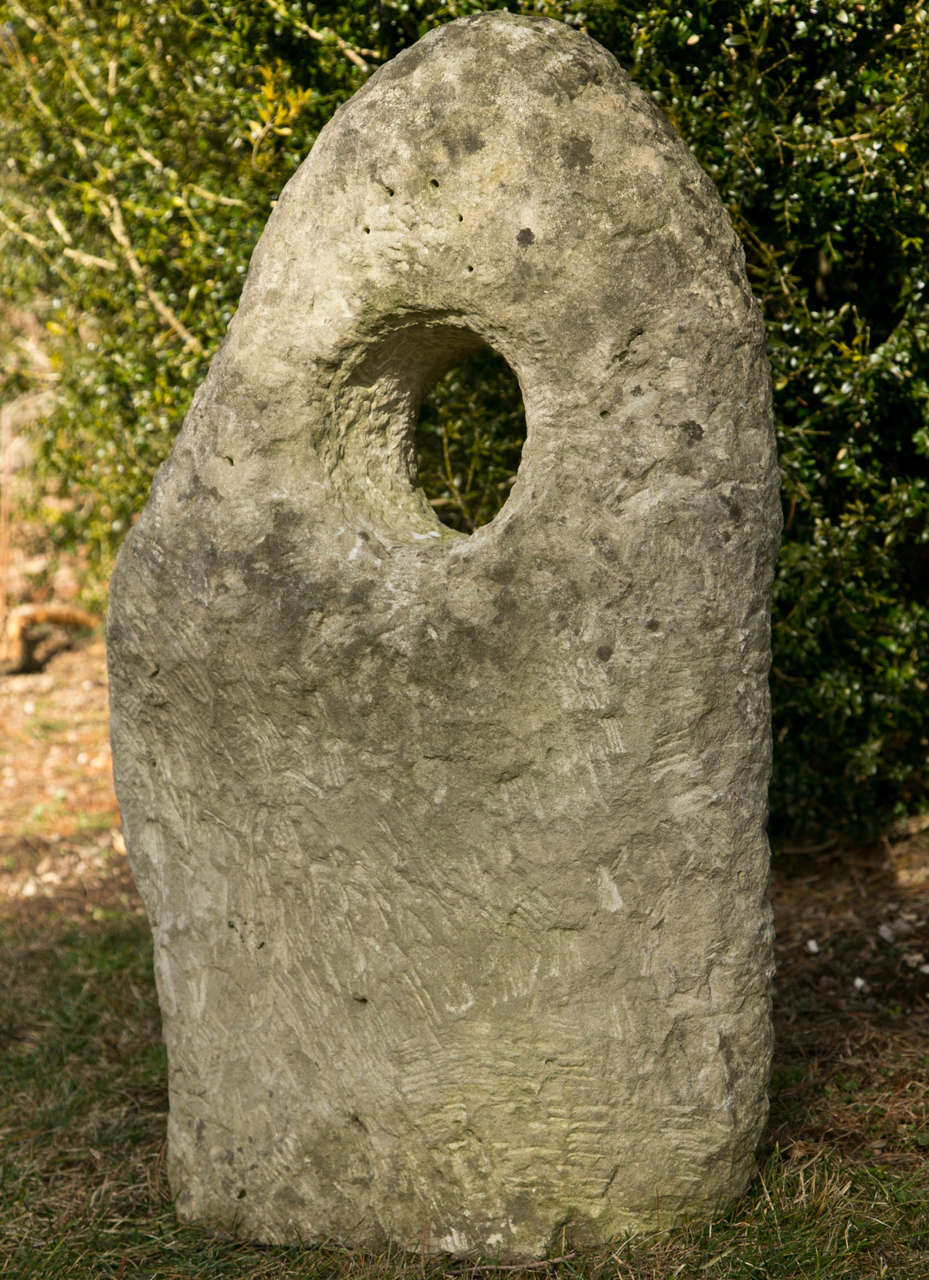 A carved stone of organic form with central sculpted opening.