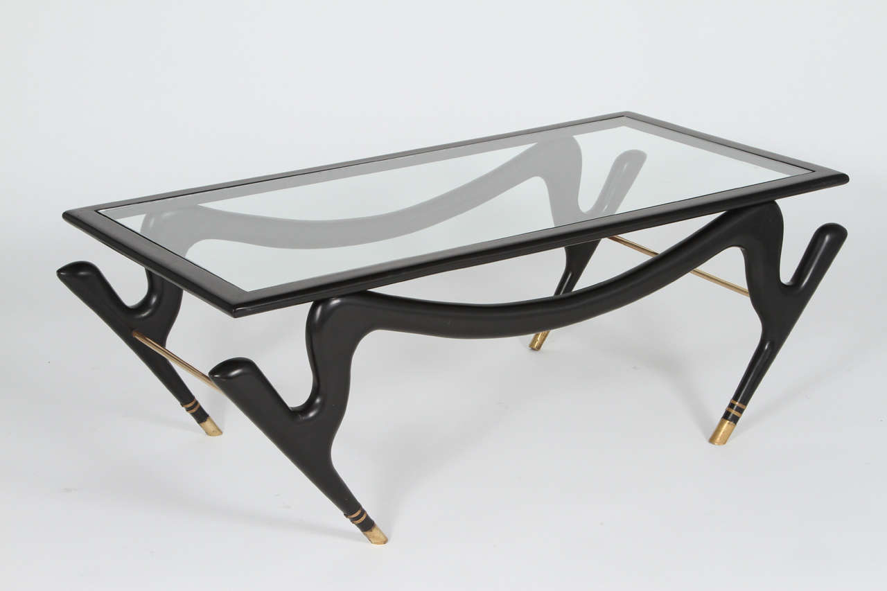 A wonderful and stylish coffee table by Eugenio Escudero. 
Mexican Modern
Has the original glass, ebonized wood, and brass wrapped feet.
c.1950's

Please call or use the contact dealer link below to reach us directly with any questions