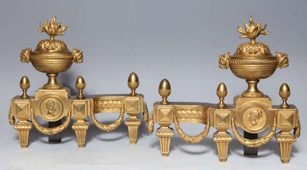 Paire de chenets de cheminée en bronze doré de style néoclassique signé Louis XVI. Les fleurons des urnes sont des flammes stylisées, les guirlandes et les portraits se combinant pour créer des bijoux élégants pour votre cheminée préférée. Signé A.