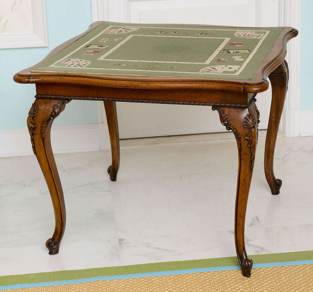 The top lined with lined with trompe l'oeil needlepoint depicting a card game. Very refined piece featuring double serpentine shape, ribbon carved frieze, shell carved cabriole legs terminating in scroll-form feet.