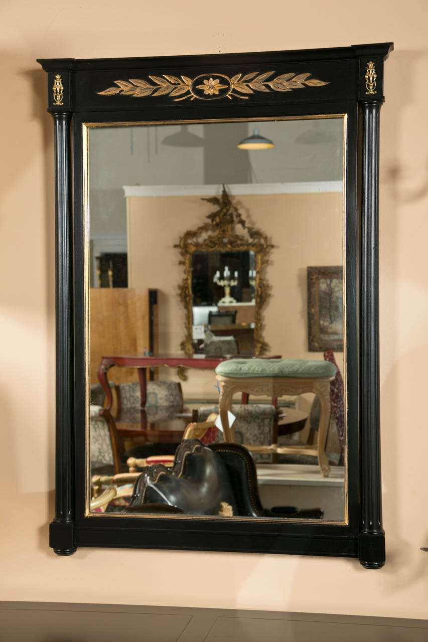 A fine pair of custom quality Ebony and Gilt gold decorated wall mirrors. The center panel flanked by a pair of column form poles. The top having a gilt gold decorated carving.