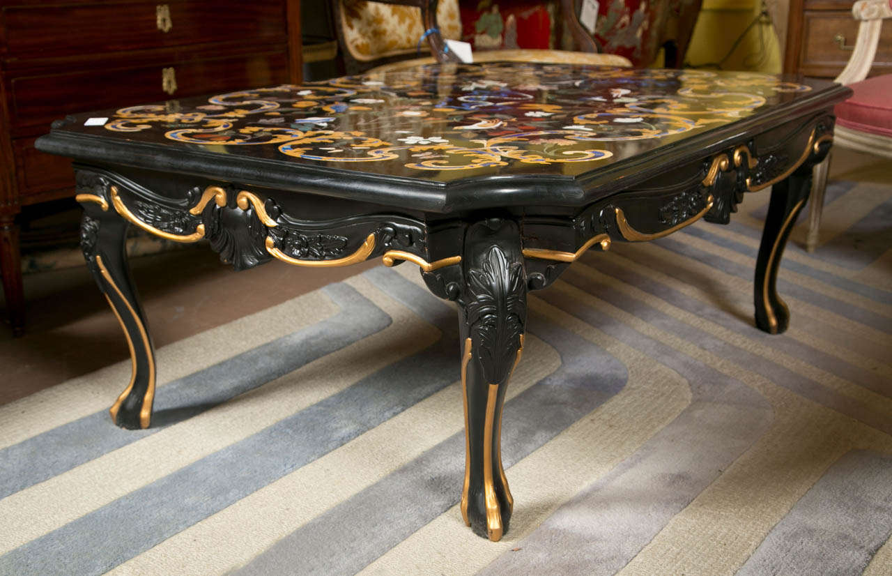 A spectacular Italian Baroque style coffee table, comes with a black based Pietra Dura exotic-stone inlaid marble top, depicting beautiful patterns of foliate, birds, and scrolls, raised on an ebonized and parcel-gilt wooden base, supported on