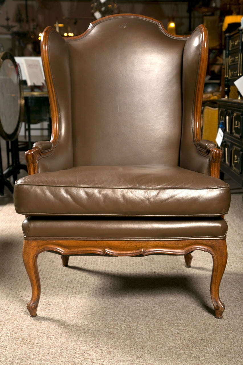 Decorative Georgian style wingback chair, walnut frame and dark brown leather upholstery, padded back and cushioned seat, raised on cabriole legs.