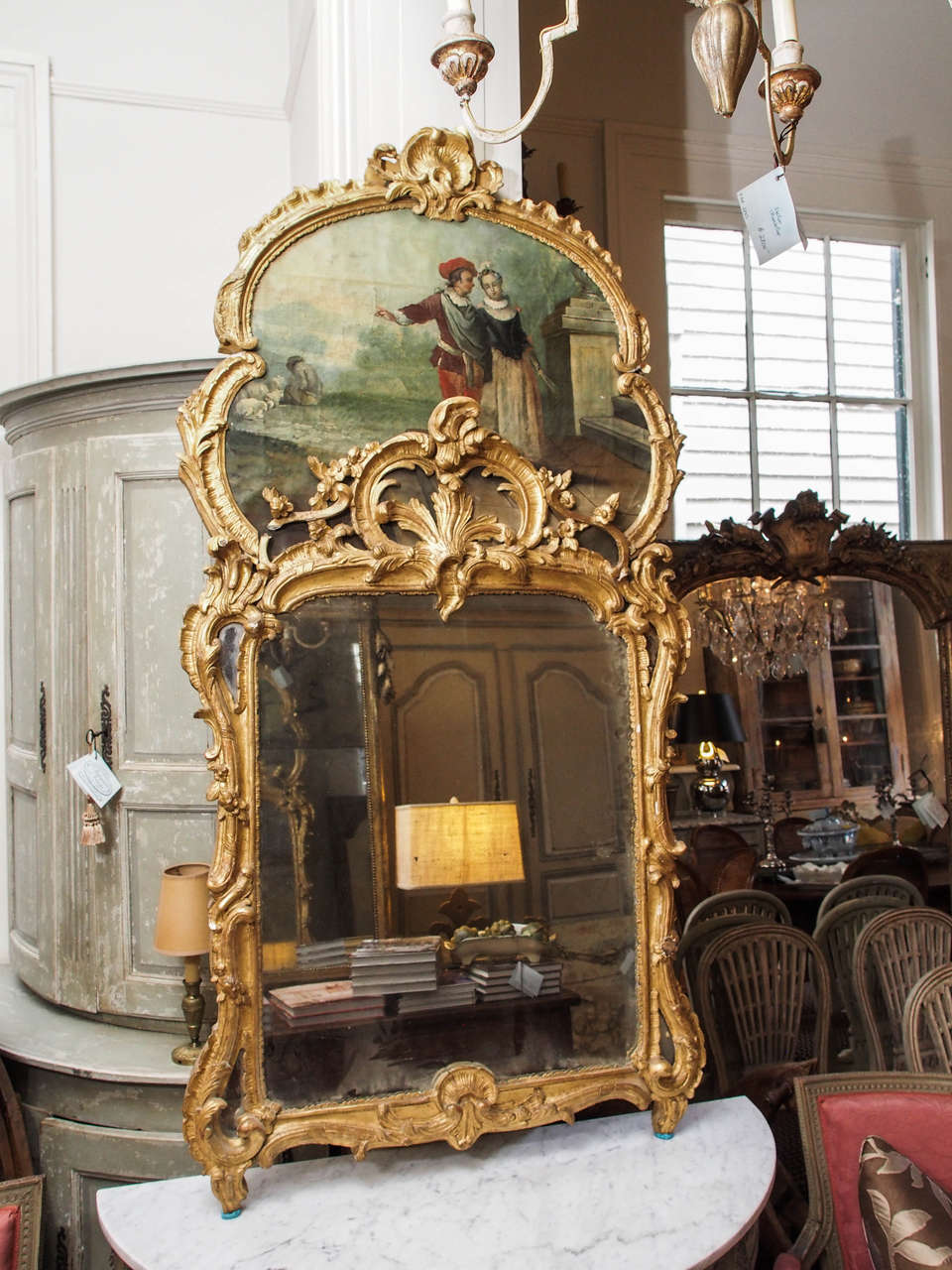 Early 19th century French Louis XV style carved giltwood trumeau. The painting is oil on canvas depicting a romantic country scene, a young couple with a shepherd and his lambs in the background.