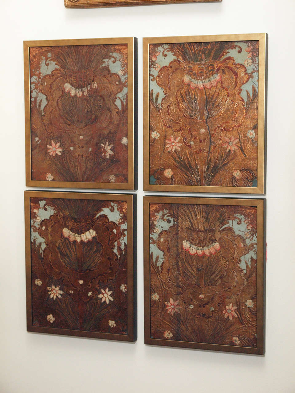 A set of four pieces of embossed, paint and gilded leather panels, now mounted and presented in a simple patinated gold tone frames.  Each panel is of the same rococo motif.  Embossed leather was popular in Europe in the 17 and 18c., and produced