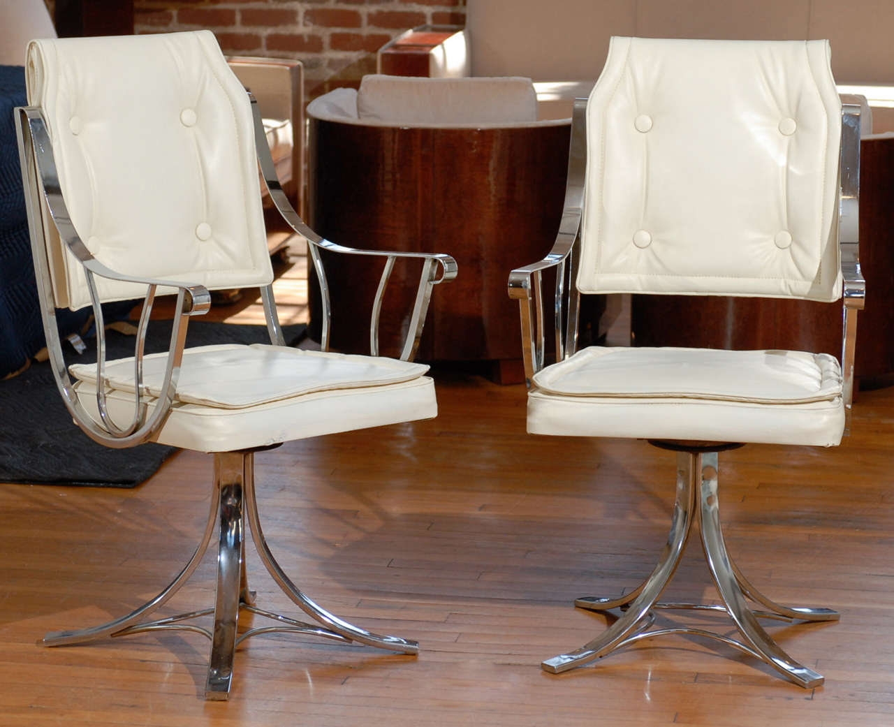 Fabulous set of four Mid Century Modern swivel armchairs with a chrome frame and the original white vinyl upholstery.  Pillow top style seat cushion and classic four button tufted back with fold over two button tuft on the reverse.  Extremely