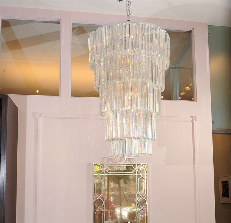 This grand chandelier in the style of Venini is truly stunning.  With five oval tiers, and over four feet, of sparkling crystals, this surely makes a statement. There are some small chips to bottom tier crystals.  Replacement crystals also included.