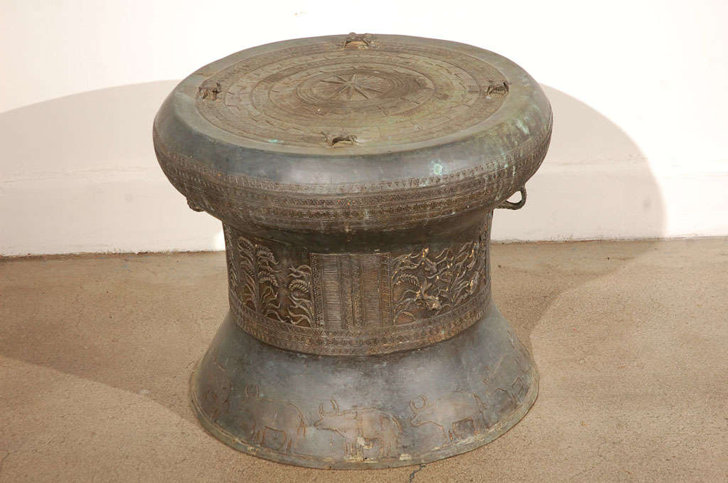 Asian cast bronze rain drum with the traditional intricate detailing and patterns carved all around both the body and the top,the top is flat centered with a raised star surrounded by concentric geometric patterned bands and with raised  frog lugs.