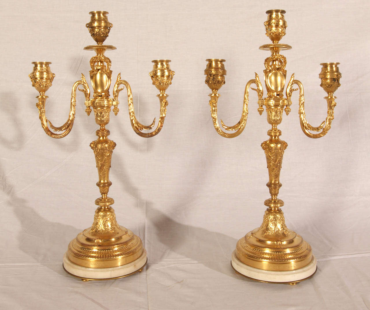 Pair of Napoleon III period candelabras in gilded brass with three light arms. White marble base. Very good condition. Normal wear consistent with age and use.