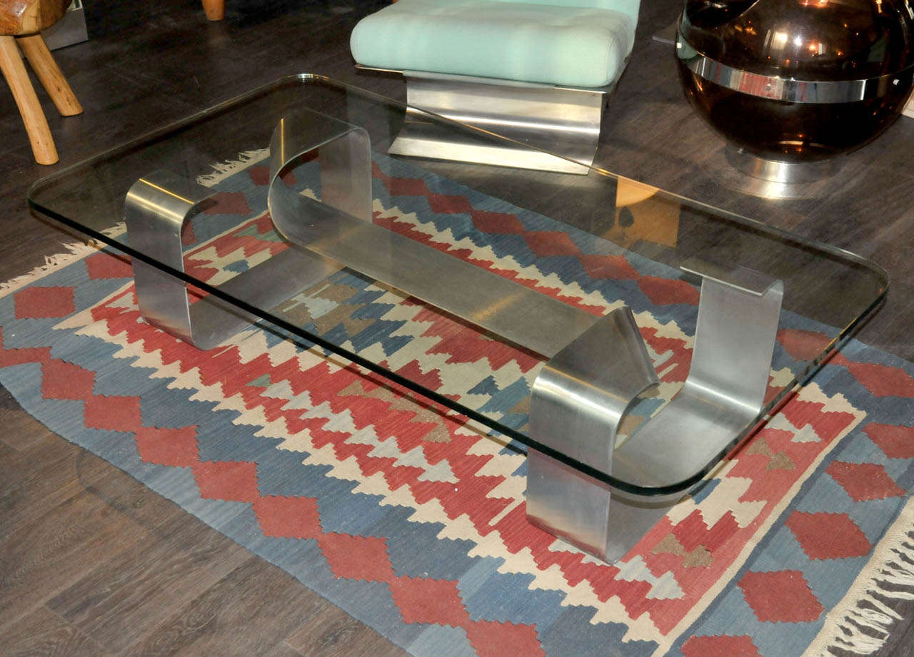 1970's coffee table with a glass top and a brushed steel base by Paul Le Geard. Documenation available on demand. Good condition. Normal wear consistent with age and use.