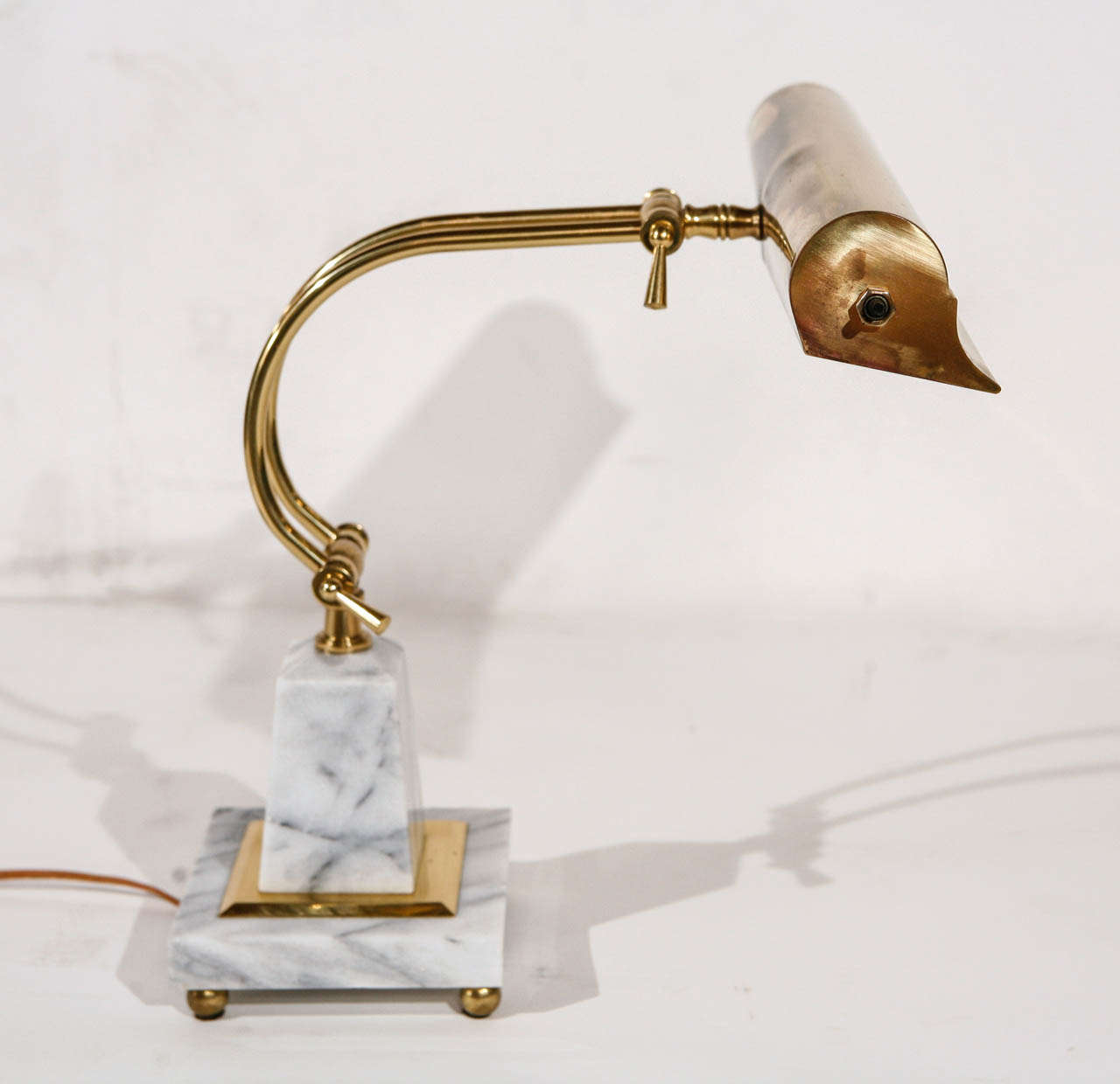 A vintage brass and marble desk lamp mounted on four brass ball feet.