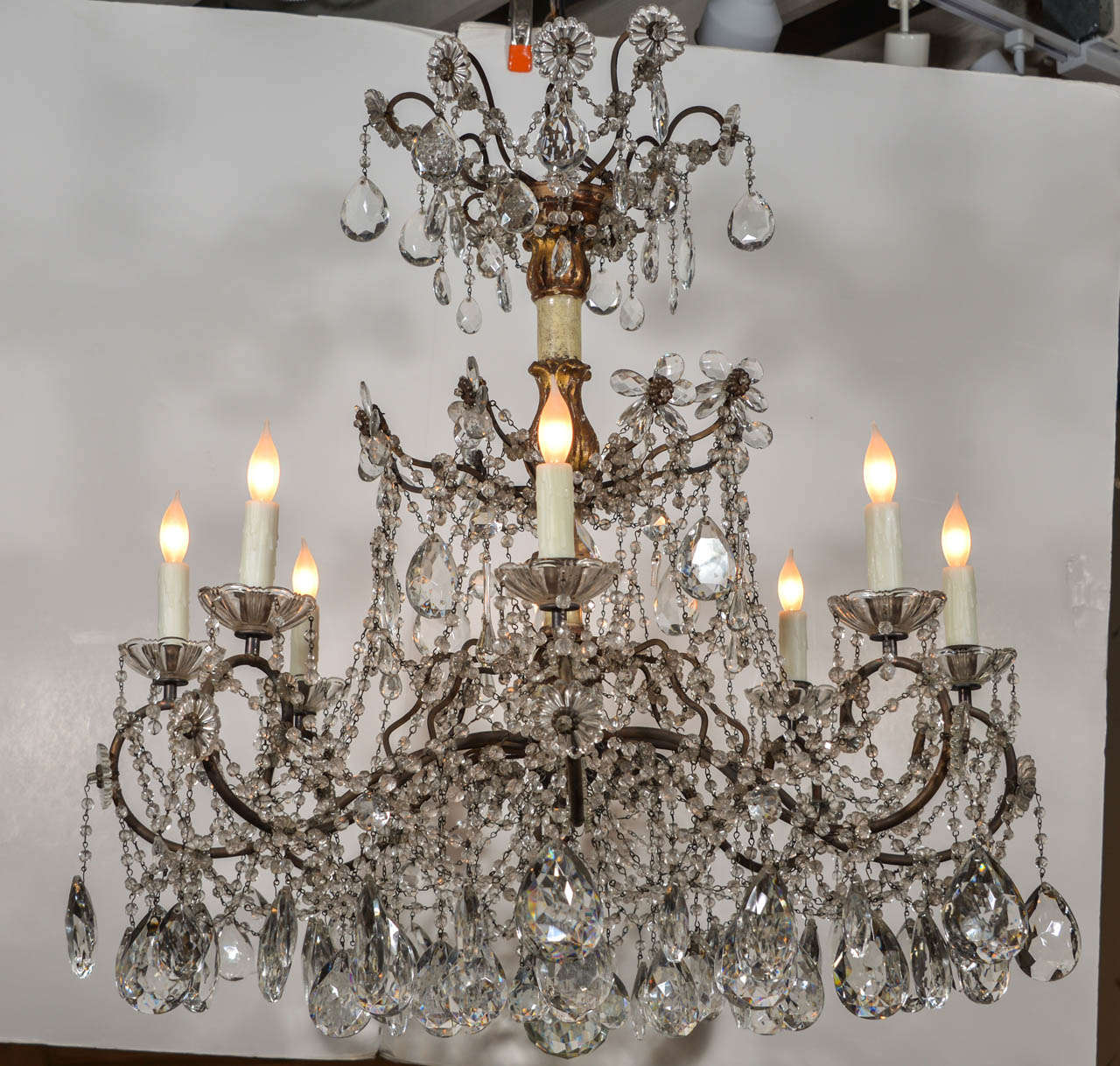 Pair of 19th century 3 tier Genovese chandeliers, each made of a ivory painted wooden stem with carved giltwood acanthus details and 8 undulating iron arms, with gilt iron and crystal flower motifs, draped in clear glass bead chains with suspended