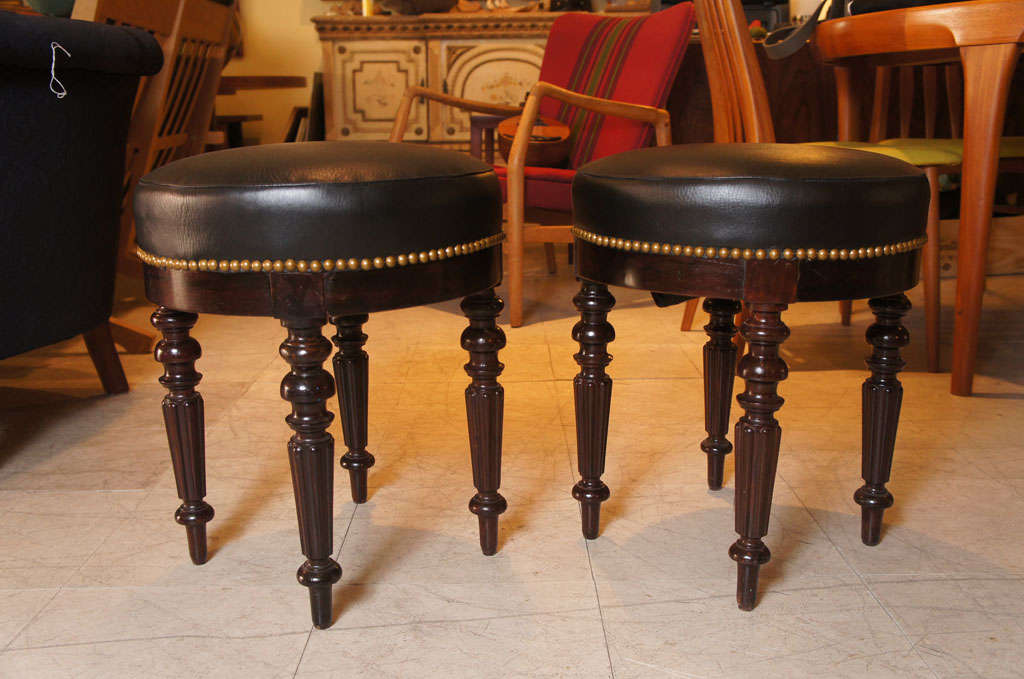 Pair of Regency period English stools, in rosewood, with elegant turned legs and newly upholstered black leather tops with brass studs