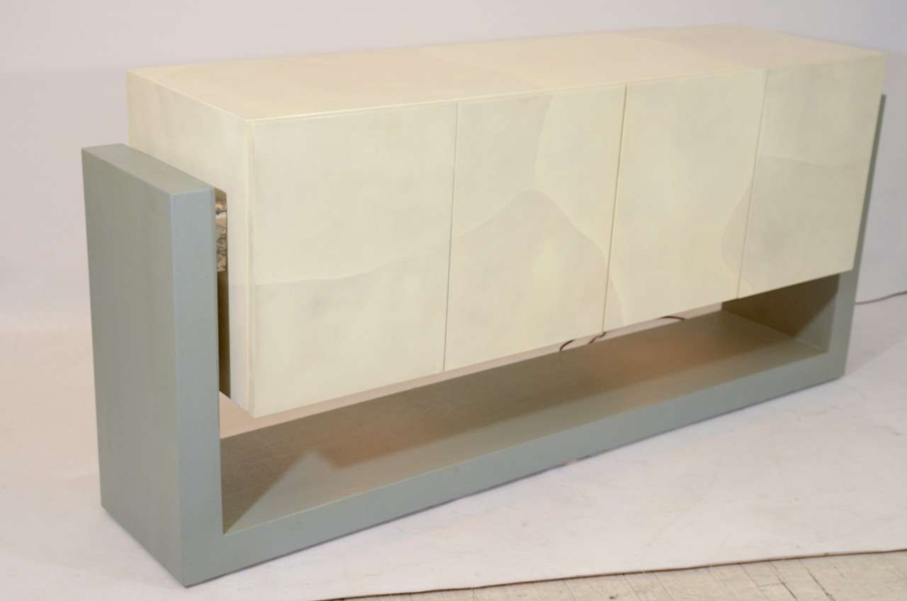 Remarkable faux parchment credenza suspended with lucite joints on a lacquered grass cloth support base. The piece is illuminated from below, which creates a lovely glow. Beautiful!  Please contact for location.