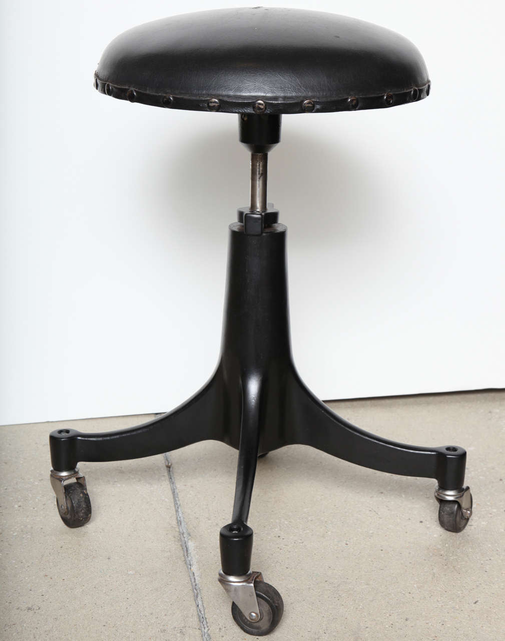 Pair of black metal stools by Bausch & Lomb.  USA, circa 1940.  Sold and priced as a pair; please contact us if you require additional matching stools.  Features an adjustable seat height, casters and black leather seat.  Ideal as counter bar