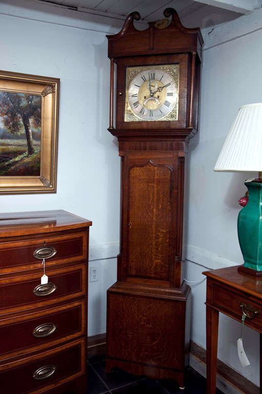 An English long case clock with swan neck pediment and column supports. The case has inlaid quarter columns, mahogany crossbanding arch door and rest on splay feet.
An elegantly unassuming clock.
The dial in brass and nickel features Roman