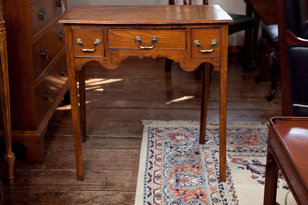 A superb example of an English country lowboy, this table appears to be showing its age in the angle of its legs, which seem to be thinking independently as to which direction they would like to go. Some would call this imperfection or defective,