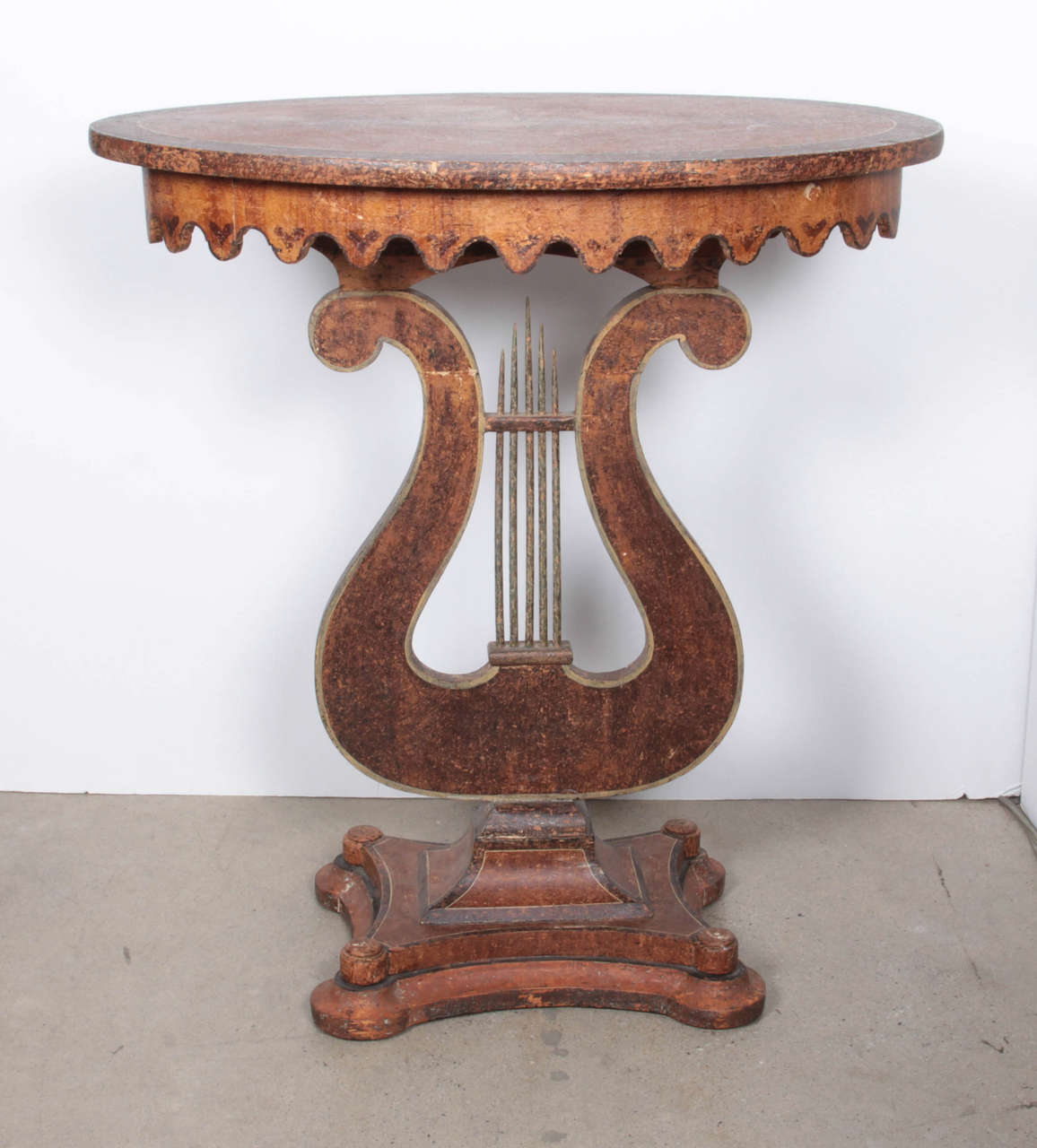 A Swedish painted side table, Circa 1860, with an oval top above a scalloped apron raised on a lyre form support and ending with a concave sided base. Dry scraped to the original paint surface.