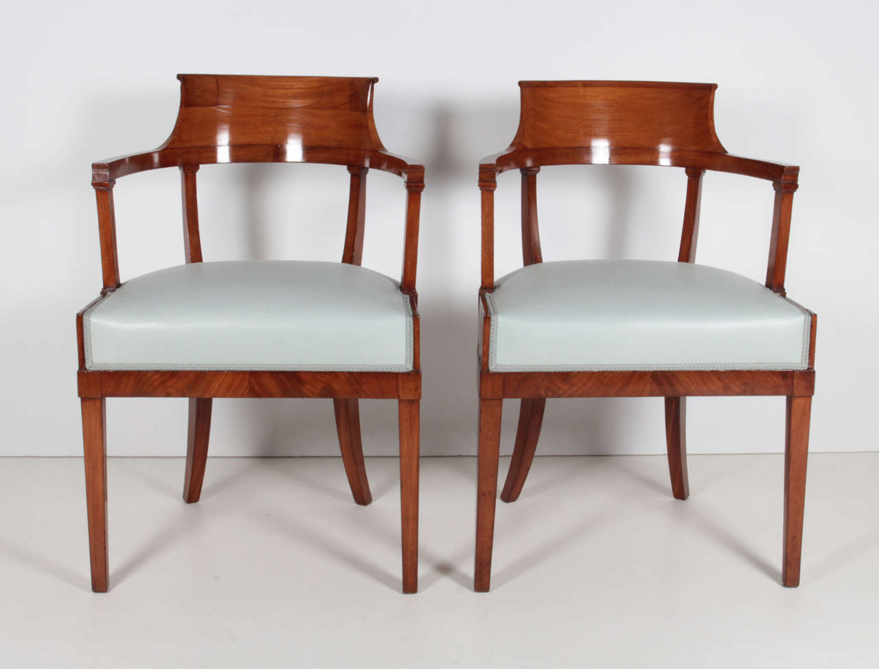 A pair of Swedish mahogany chairs, Late 19th Century, by Alfred Grenander - Architect. Born. Skovde, Sweden circa 1863 - Died -  Berlin, Germany 1931. with a scrolled and curved backrest, above a wide frieze and upholstered seat, on square tapering