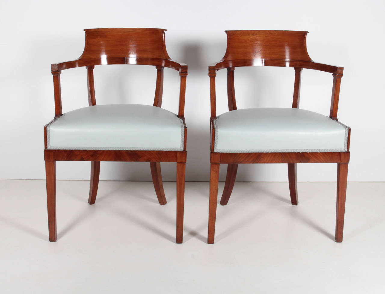 A pair of Swedish mahogany chairs, Late 19th Century, by Alfred Grenander - Architect. Born. Skovde, Sweden Ca. 1863 - Died -  Berlin, Germany 1931. with a scrolled and curved backrest, above a wide frieze and upholstered seat, on square tapering