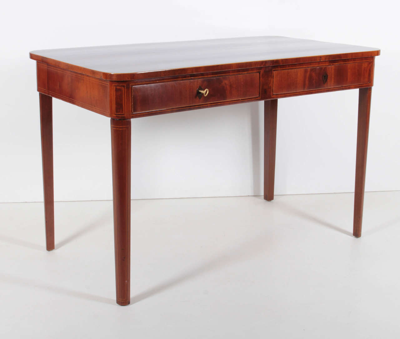 A Danish Late Empire mahogany line inlaid bureau plat, Circa 1830, the rectangular top with rounded corners above two frieze drawers raised on quarter rounded and tapered legs.