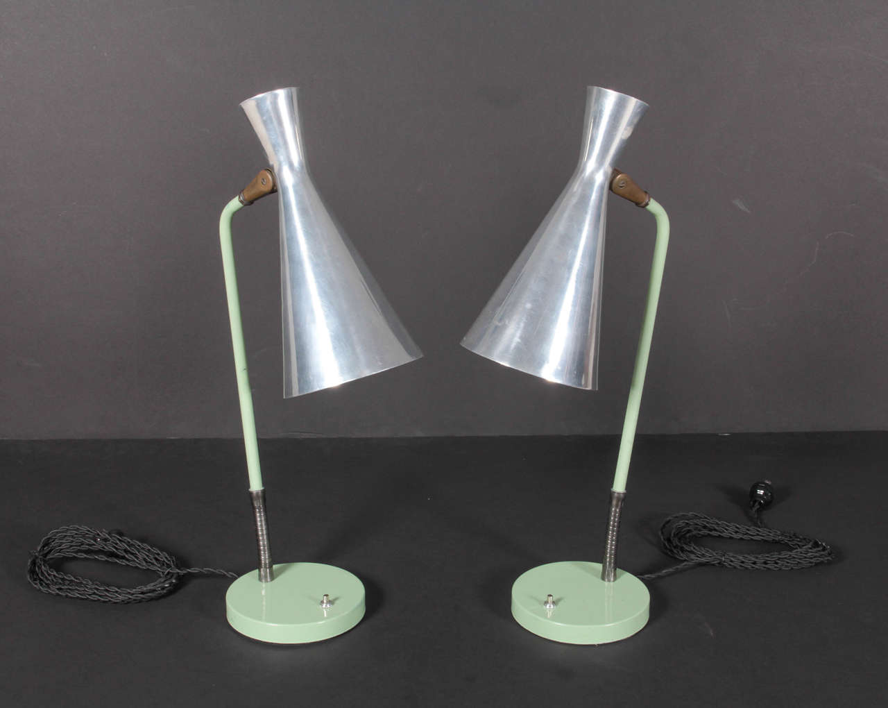Green-painted steel bases with a flexible brass stem supports a polished aluminum double-cone shade. Newly rewired for US usage and fitted with LED bulbs. A slight dent to top of one shade, minor scratching to polished shades and original paint.