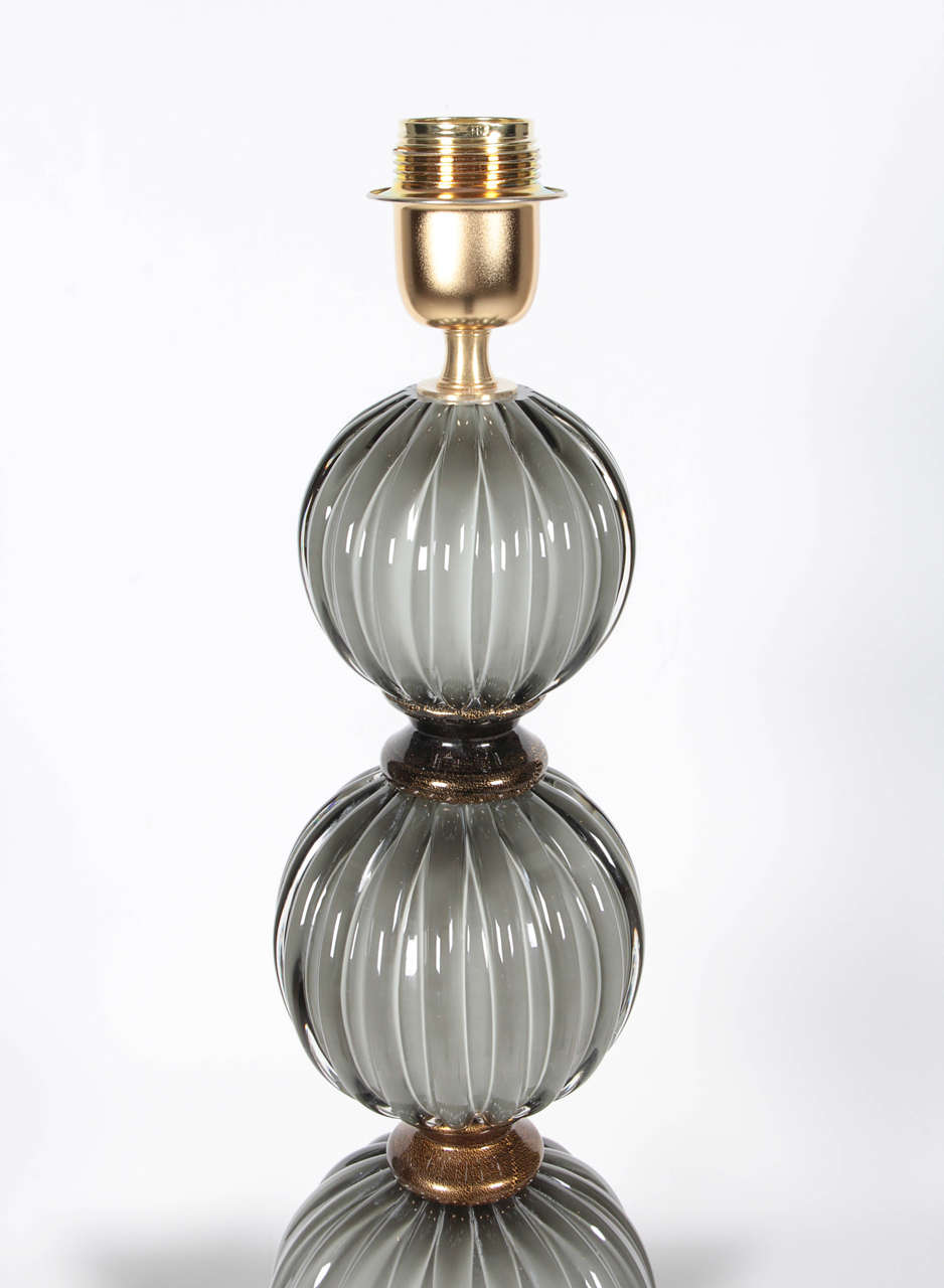 Beautiful pair of heavy Murano glass table lamps in the style of Barovier. The glass color is a soft grey infused with 23-carat gold flecks, creating a shimmery, metallic look. Wired for U.S. standards. Measurements below are for glass base up to