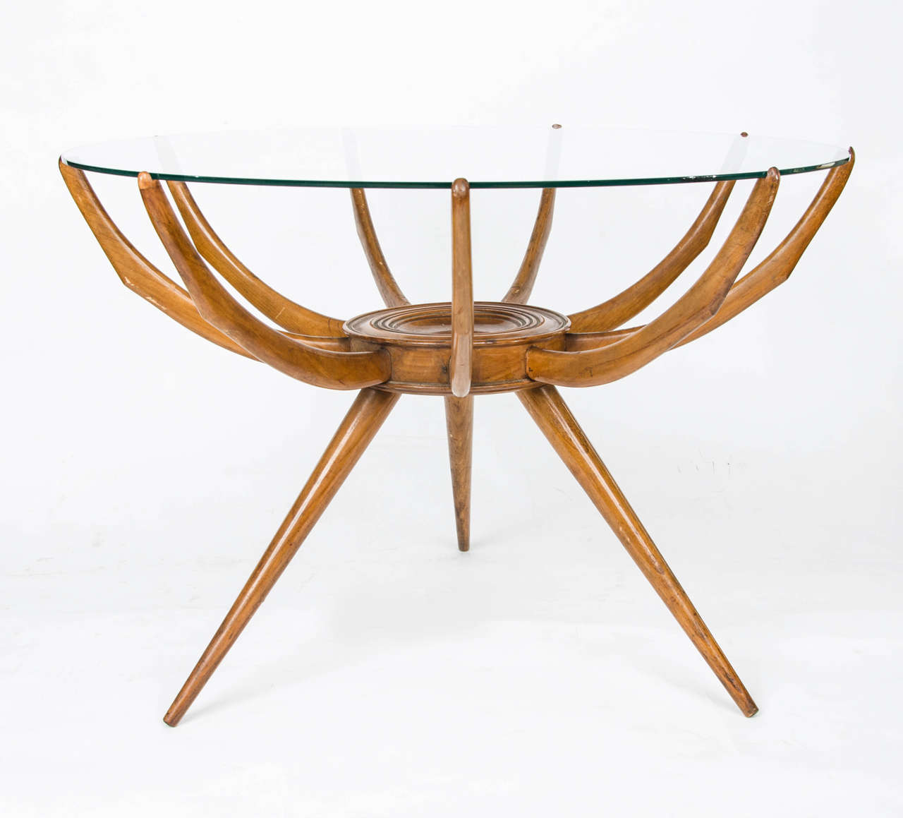 Circular 'spider' table by Carlo di Carli.
Code: FT418.
1950s Italian coffee table of carved wood frame with nine arms supporting a glass top, standing on three splayed tapering legs.