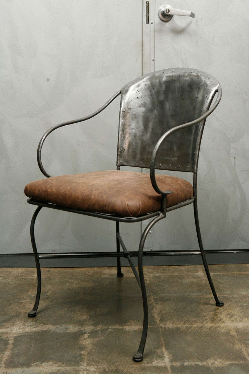 This is a gorgeous Hand Wrought Iron chair that has been polished to reveal a beautiful finish. The arms and legs of this piece have a lovely shape with a crossed stretcher below the seat. The seat cushion has been newly upholstered with a soft